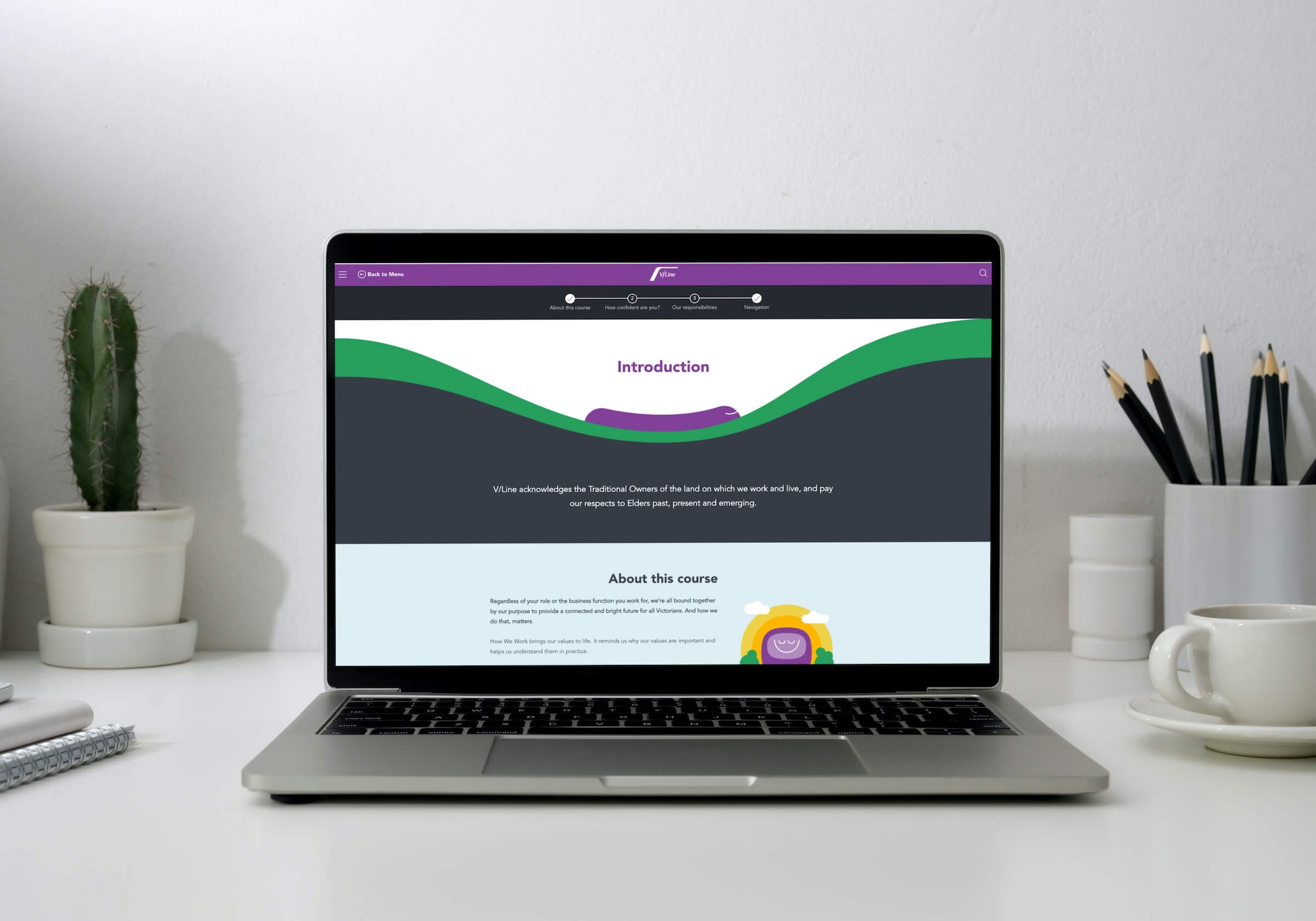 A laptop on a desk displays an online course introduction page. The desk also holds a cactus, a notebook, and a cup with saucer, set against a white wall—perfect for staying organised and ready to contact your tutor if needed.