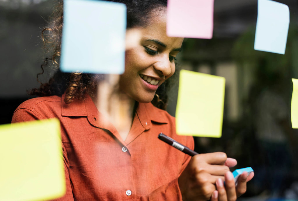 Woman writing on sticky notes.